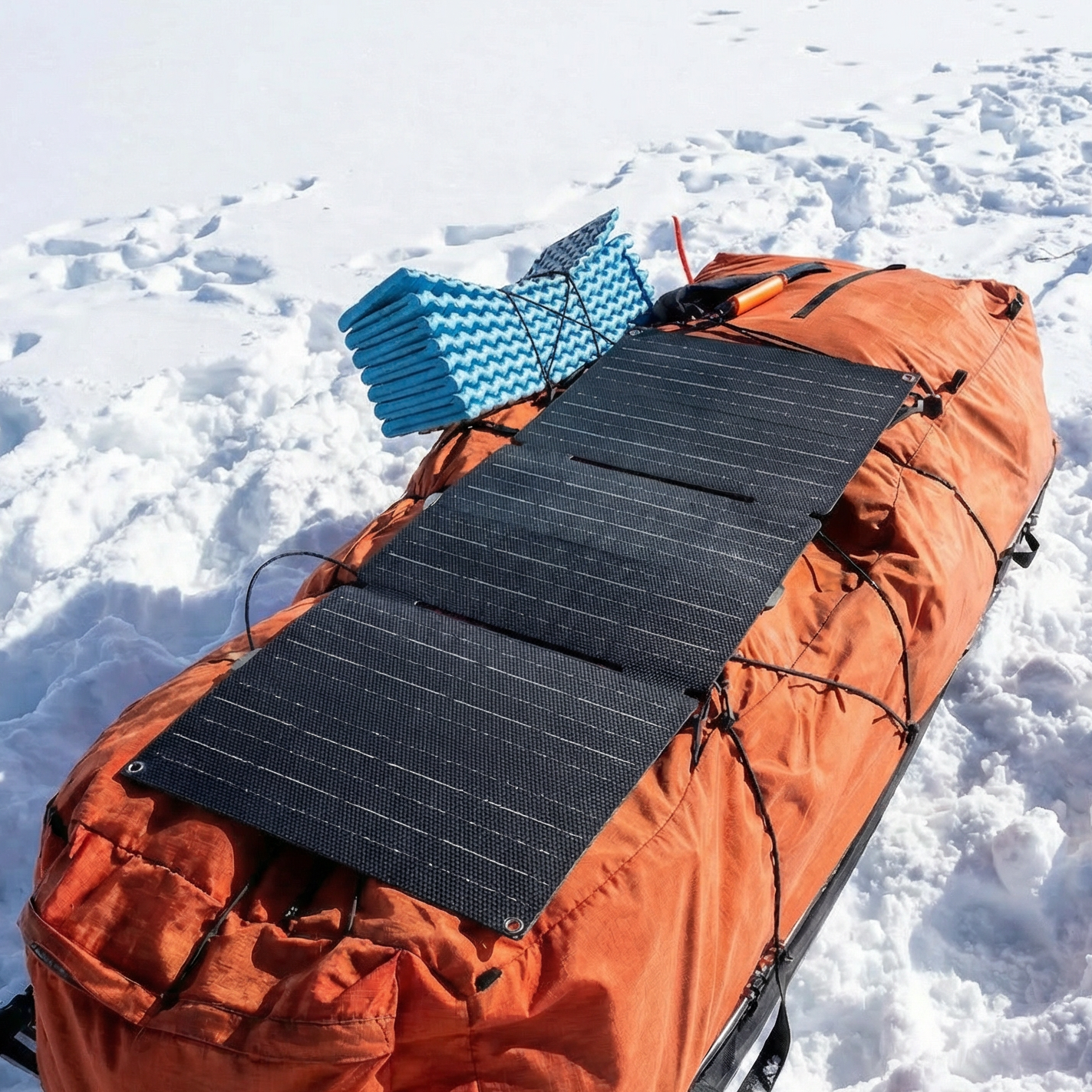 Orange backpack with a solar panel attached on a snowy landscape
