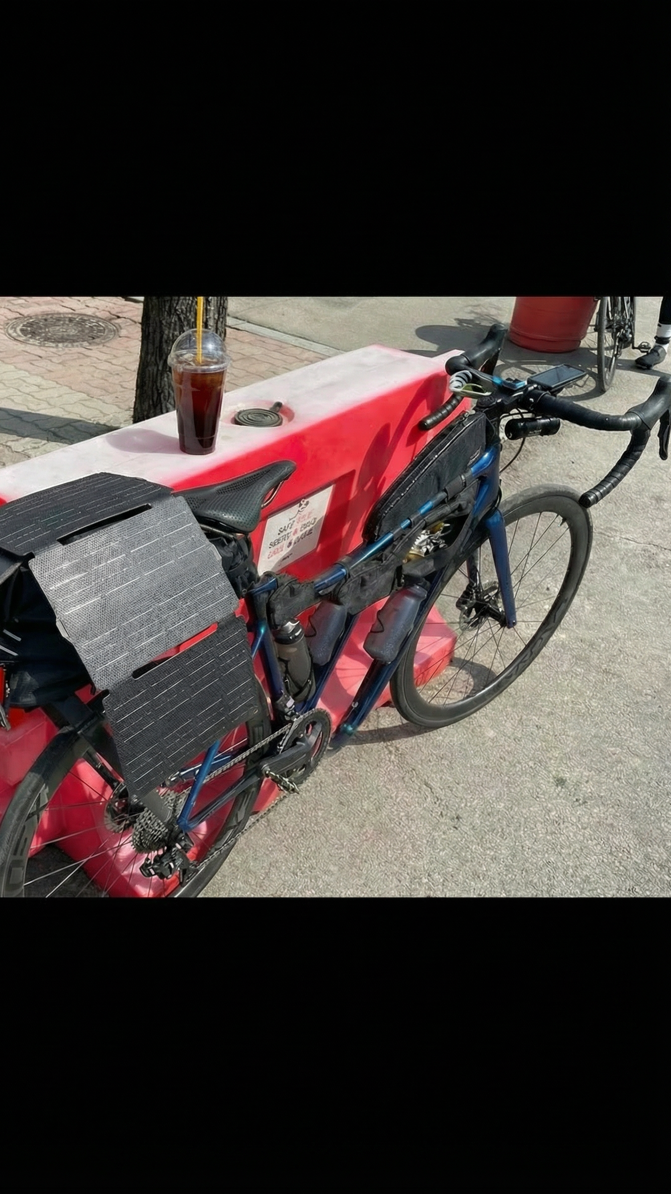 Bicycle attached to a red bike rack on a sidewalk